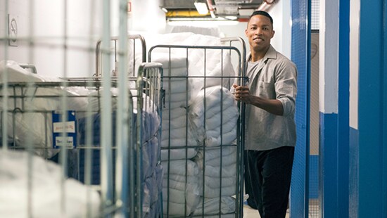 Man pushing a large cart with folded commercial laundry