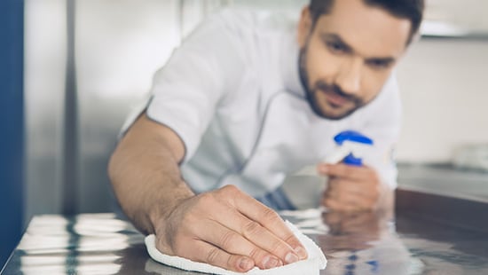 Man cleaning and sanitizing a table.